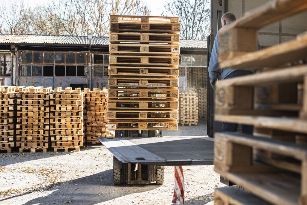 Forklift loading a stack of pallets onto a truck for haul-off